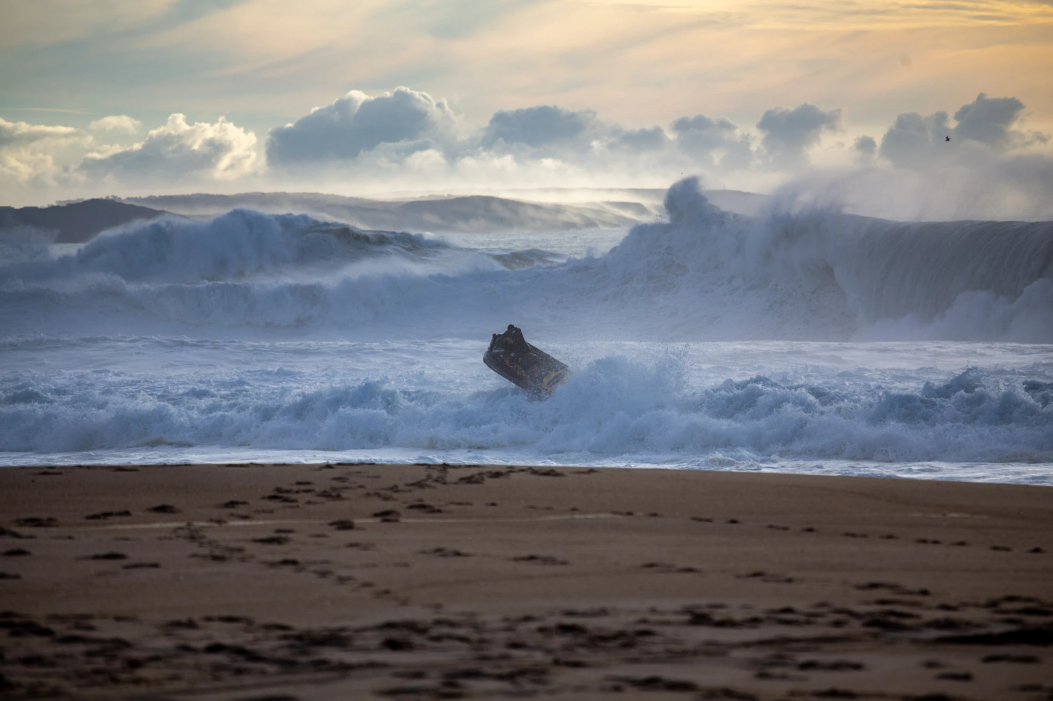 A jet ski is flung near-vertical by the impact of a colossal Nazaré wave, a wall of white foam and spray exploding around it, the whole scene shot through with dramatic storm light.